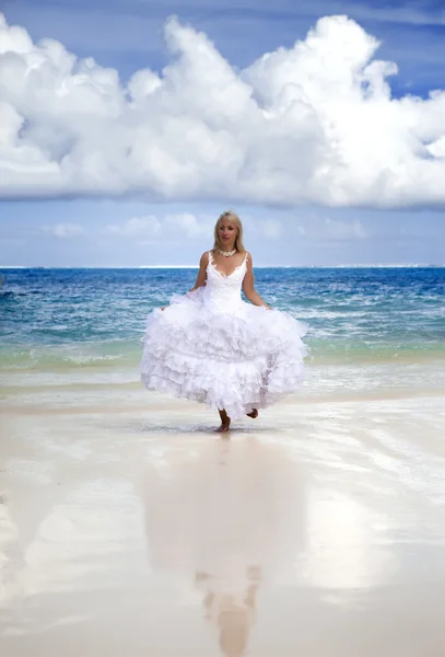 Mooie vrouw in een bruiloft jurk loopt op golven van de zee — Stockfoto