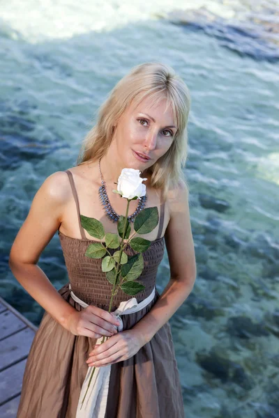 Hermosa mujer en un vestido largo en una plataforma de madera sobre el mar —  Fotos de Stock