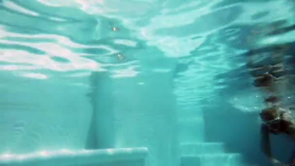 De mooie jonge vrouw met lange haren zwemmen in het zwembad onder water — Stockvideo