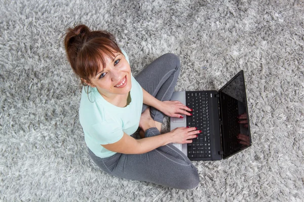 Leende kvinna som använder laptop hemma — Stockfoto