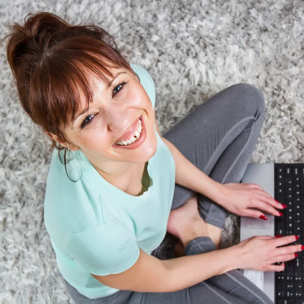 Mulher sorridente usando laptop em casa — Fotografia de Stock