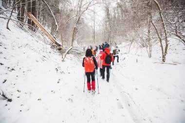Karlı yolda yürüyüş yapan sırt çantalı yürüyüşçüler. Kış günü birlikte yürüyen bir grup insan. Arka plan.