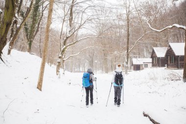 Karlı yolda yürüyüş yapan sırt çantalı yürüyüşçüler. Kış günü birlikte yürüyen aktif insanlar. Arka plan.