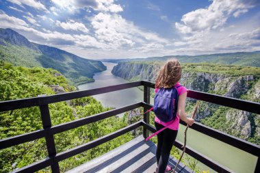 Little girl at viewpoint, beautiful nature landscape, amazing view on gorge Danube river , sunny spring day. Travel destination Serbia.