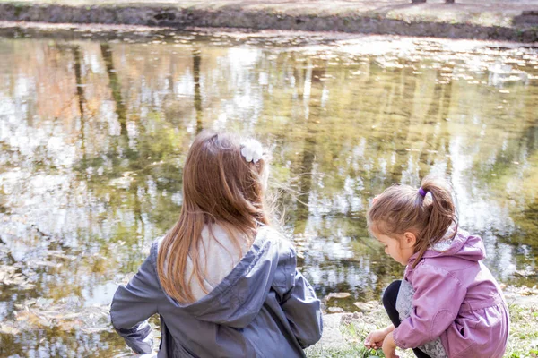 Две Маленькие Девочки Играют Парке Возле Озера Отражение Деревьев Воде — стоковое фото