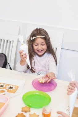 Smiling Little girl decorating part of Christmas gingerbread house at home, Xmas collection 