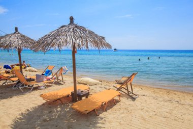 Yaz tatili ve seyahat konsepti - Kum sahilde şezlong ve güneşlik - Arka planda güzel deniz - Rahatlatıcı yaşam tarzı