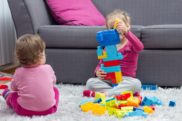 Kleines Mädchen und Baby spielen zusammen — Stockfoto