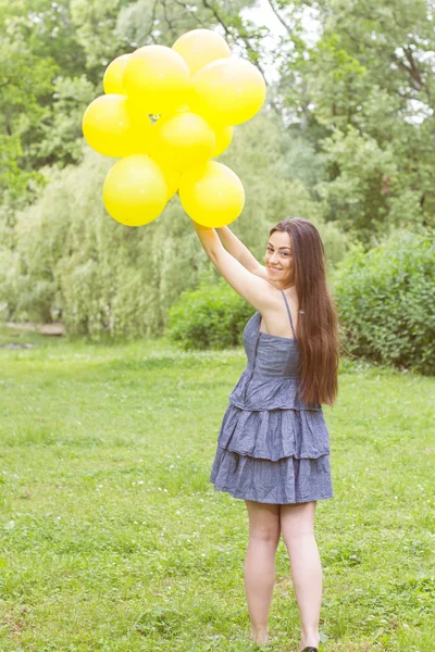 Attraente giovane donna con palloncini gialli — Foto Stock