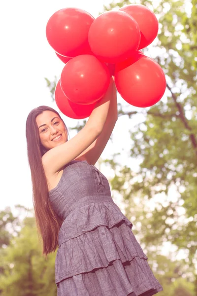 Çekici genç kadın kırmızı balonlar ile — Stok fotoğraf