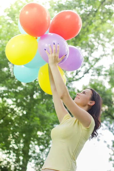 Glückliche junge Frau mit bunten Luftballons — Stockfoto