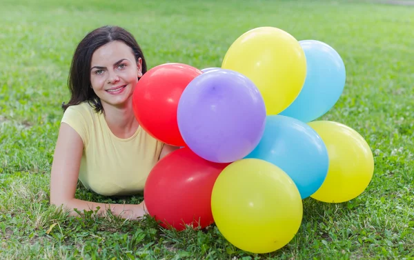 Glückliche junge Frau mit bunten Luftballons — Stockfoto