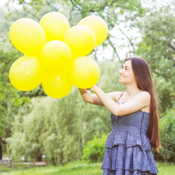 Mujer joven feliz con globos amarillos — Foto de Stock