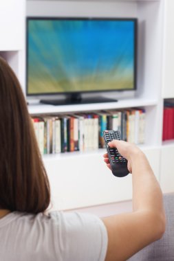Evde televizyon izleyen bir kadın.