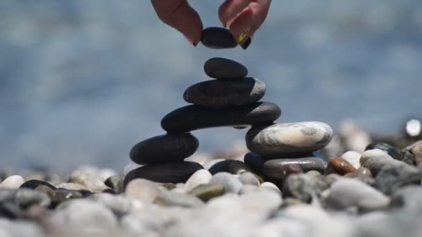 Feminino mão construindo uma torre de pedra. — Vídeo de Stock