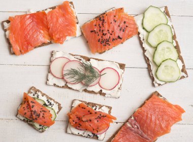 Kanepe manzarası ve somon ve sebzeli sandviçler ahşap arka planda.