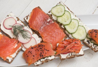 Somon ve sebzeli kanepeler ve sandviçler ahşap arka planda