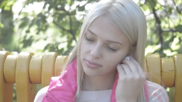 Молода красива жінка слухає музику в парку — стокове відео