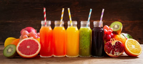 bottles of fruit juice with fresh fruits on a wooden table