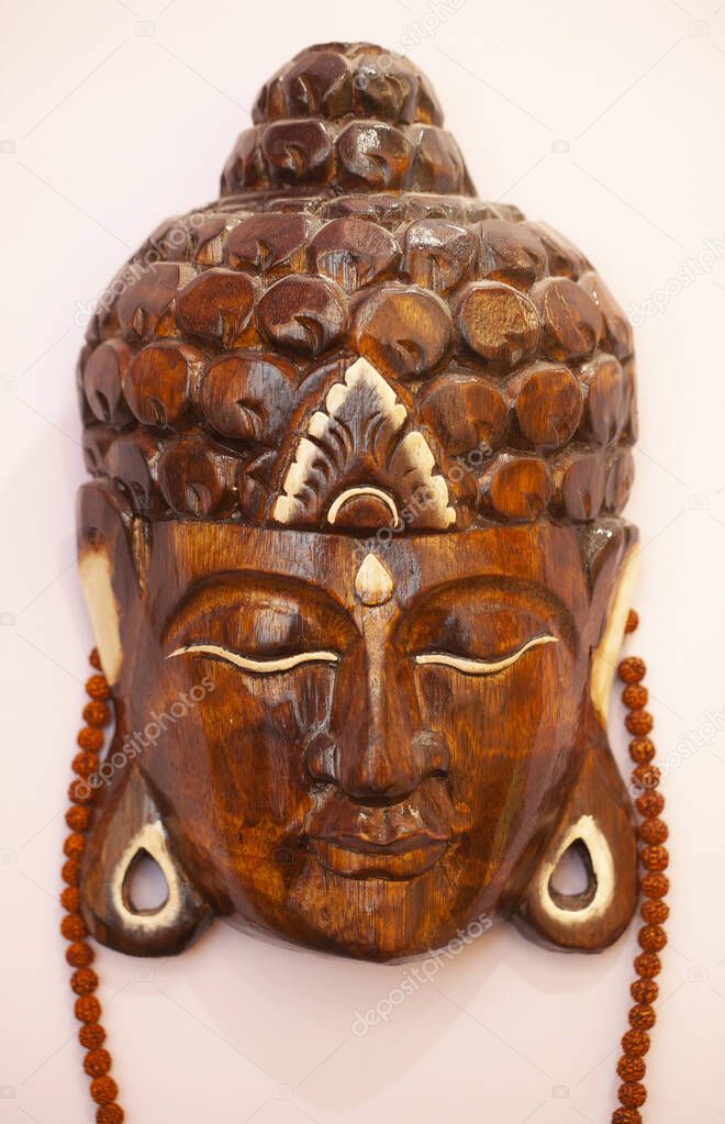 Buddha head made of wood hanging on wall