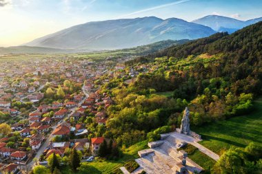 Bulgaristan 'ın Hristo Botev anıtı ve görkemli dağ arkaplanının yer aldığı Kalofer kentinin havadan görünüşü. Tarihin, doğanın ve geleneğin çarpıcı bir karışımı..