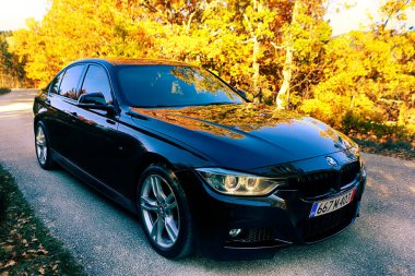 VELINGRAD, BULGARIA - NOVEMBER 4, 2025: Side view of BMW 3 Series F30 M Sport sedan parked along a mountain road during autumn.
