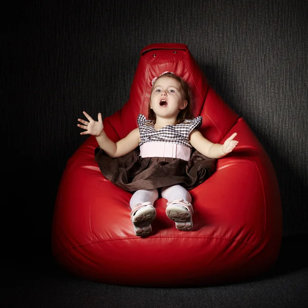 Malá dívka sedící na červené beanbag — Stock fotografie