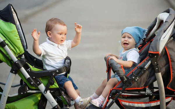 Мальчик и девочка сидят в детских колясках — стоковое фото