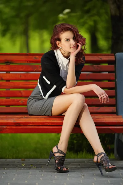 Joven hermosa chica sentado en banco en parque —  Fotos de Stock