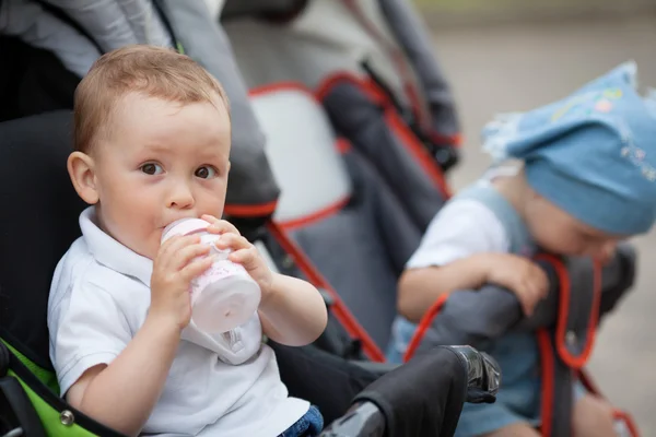 可爱的宝宝喝果汁坐在婴儿车 — 图库照片