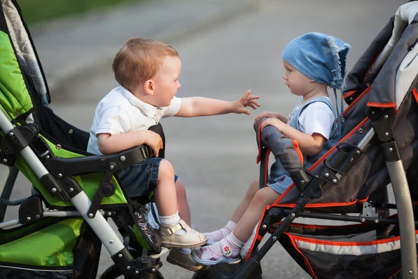 Niño y niña sentado en cochecitos de bebé — Foto de Stock