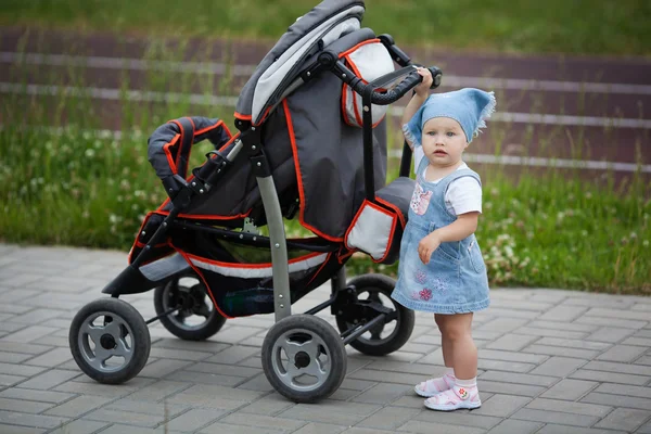 Little funny girl with baby carriage Royalty Free Stock Images