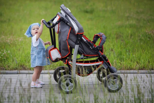 Little funny girl with baby carriage Stock Photo