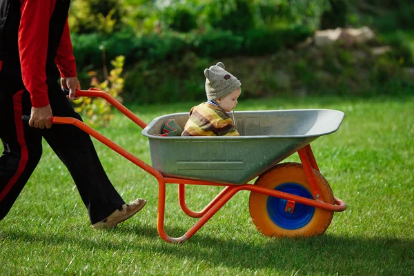 Cute little boy sitting in wheelbarrow — Stock Photo, Image