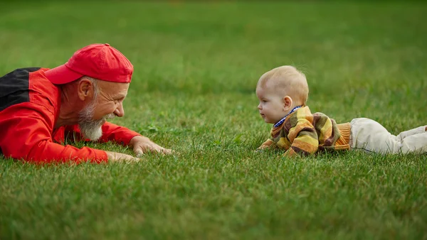 Farfar och sonson liggande på gräs — Stockfoto