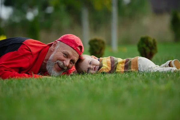 Παππού και εγγονό ξαπλωμένος στο χόρτο — Φωτογραφία Αρχείου