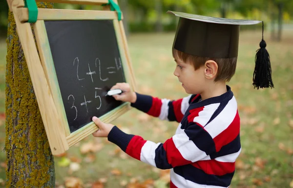 Pequeño niño feliz escribiendo en pizarra — Foto de Stock