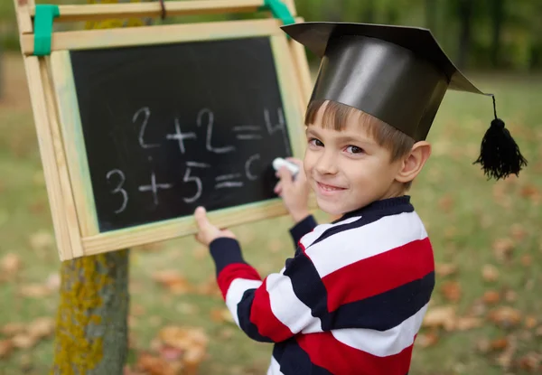 Pequeño niño feliz escribiendo en pizarra — Foto de Stock