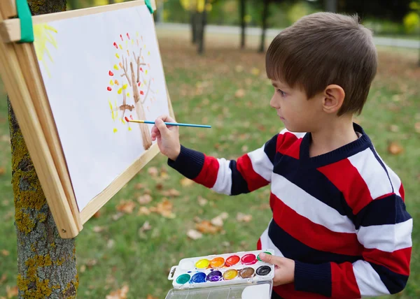 Маленький счастливый мальчик рисует в парке — стоковое фото