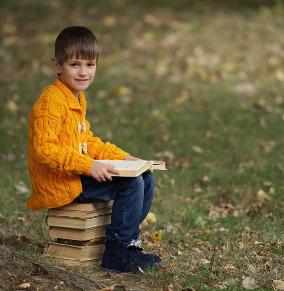 Kleine jongen zittend op stapel boeken — Stockfoto