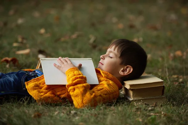 Little boy sying på trave böcker — Stockfoto