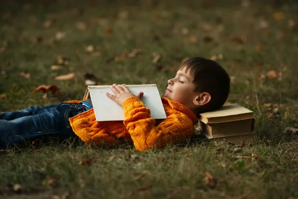 Küçük çocuk sying kitap yığını üzerinde — Stok fotoğraf