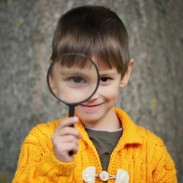 Little happy boy with magnifying glass — Stock Photo, Image