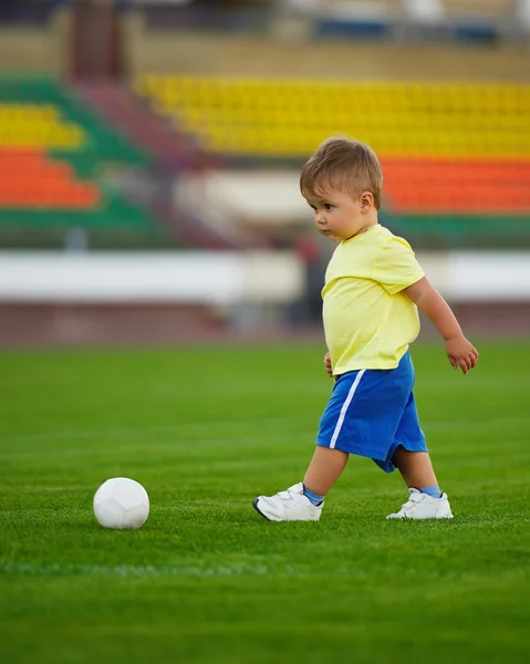 Маленький смешной мальчик на футбольном стадионе — стоковое фото