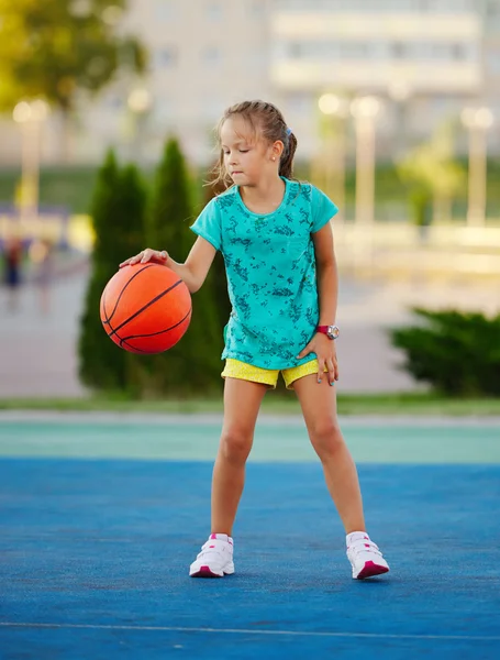 photo of little cute girl playing basketball outdoors