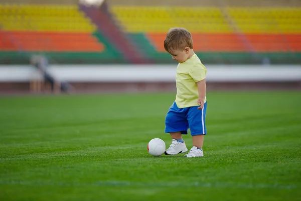 Маленький смешной мальчик на футбольном стадионе — стоковое фото