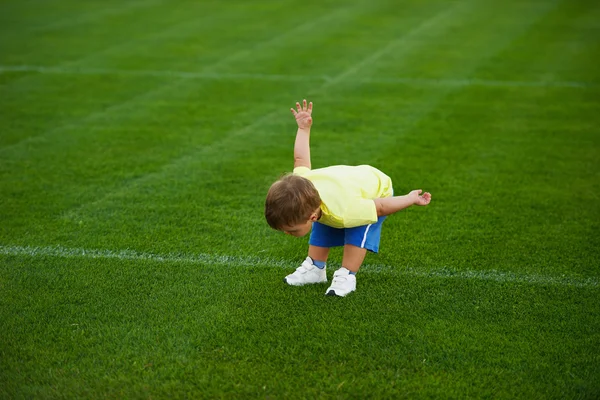 Маленький смешной мальчик на футбольном поле — стоковое фото