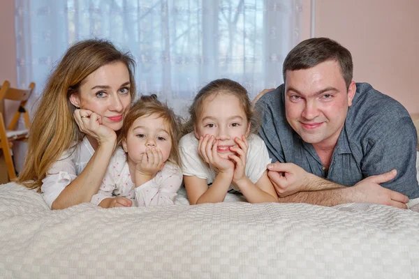 Jovem família feliz deitada na cama — Fotografia de Stock