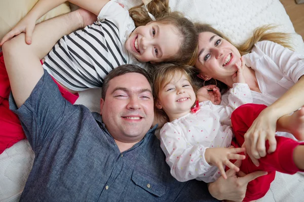 Glückliche junge Familie liegt im Bett — Stockfoto