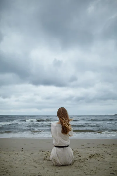 Jeune belle femme sur la plage froide et venteuse — Photo